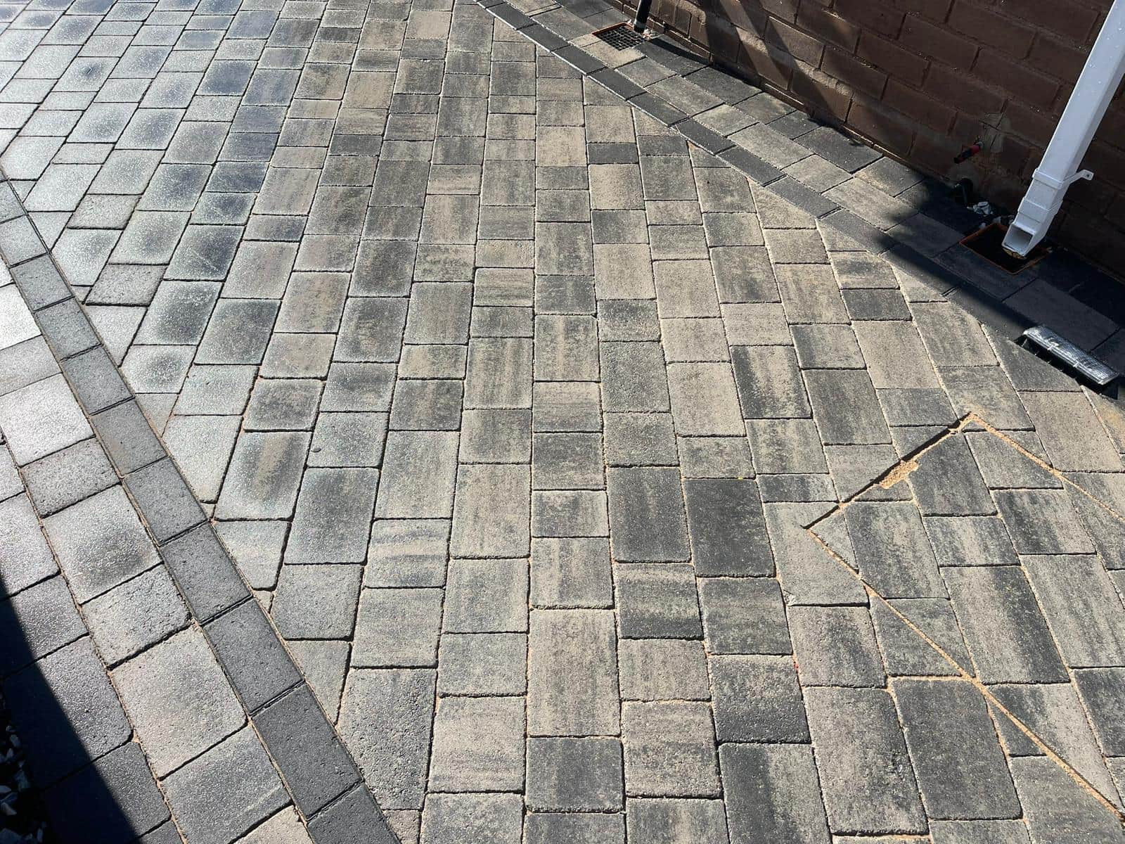 Grey block-paved driveway with a contrasting border outside a house