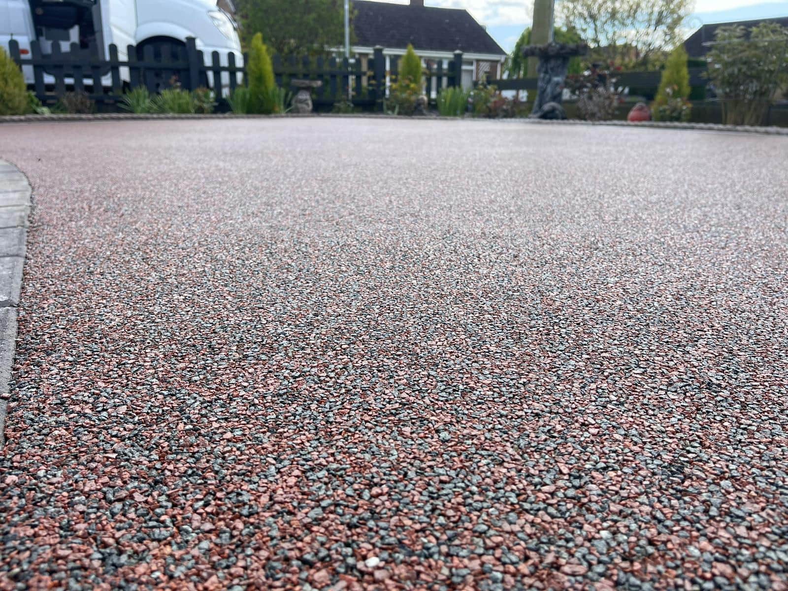 Resin-bound aggregate surface with a block-paved edge beside a lawn
