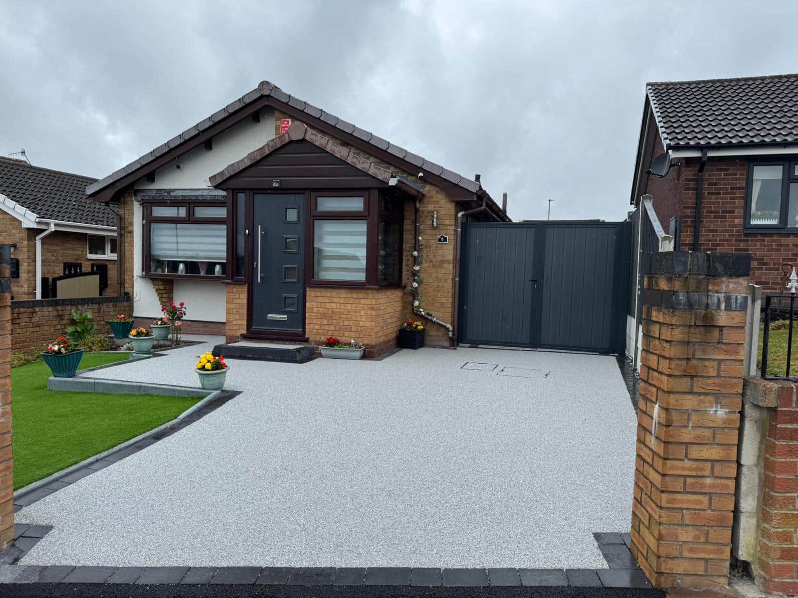 Completed light-grey resin driveway leading to a bungalow and garage